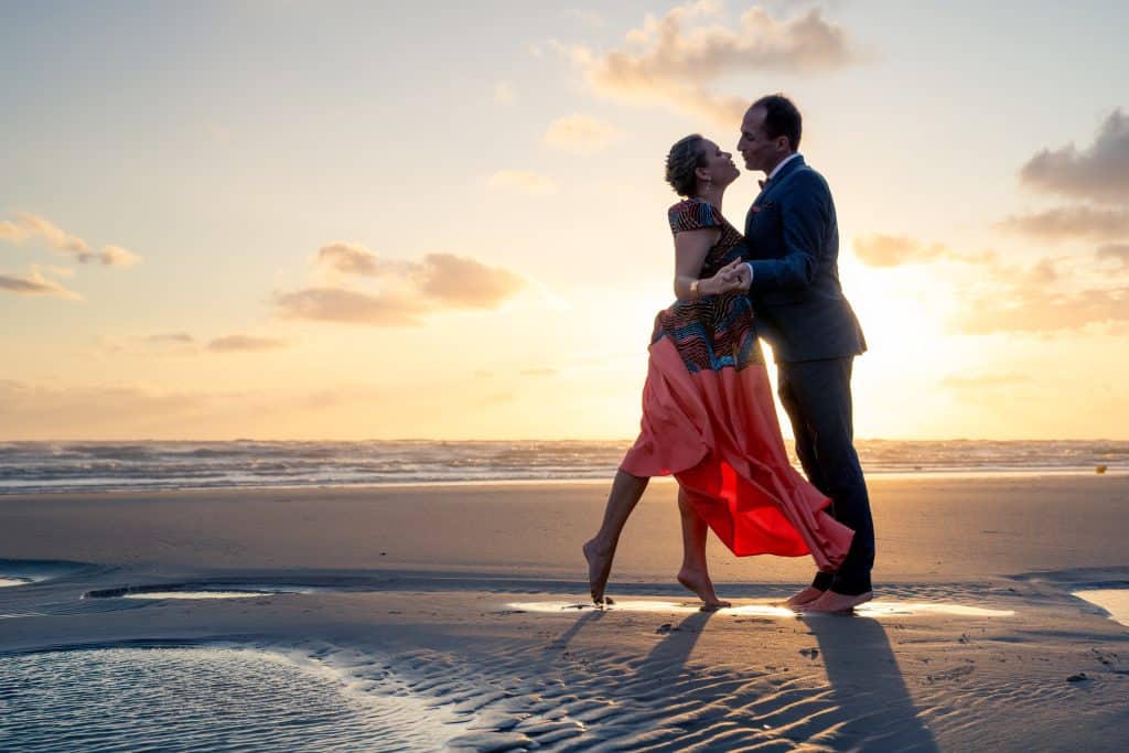 Photographe mariage et famille à Lille : couple de mariés enlacés sur la plage au coucher du soleil